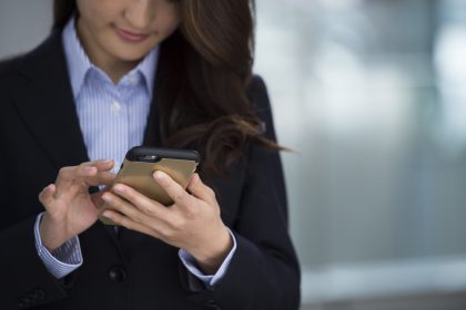 Young woman wearing a suit is using a smartphone